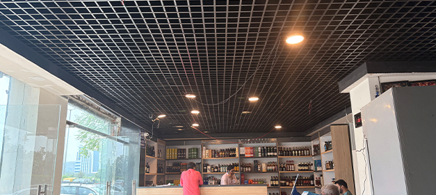 Liquor store interior with wall-mounted bottle display racks and grid ceiling