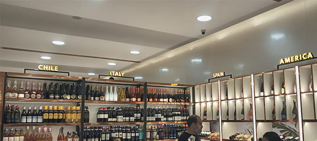 Liquor display racks organised by country categories under recessed lighting
